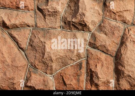 Die Oberfläche des Mauerwerks besteht aus grob behauenen großen roten Steinen, die miteinander verbunden sind. Stockfoto