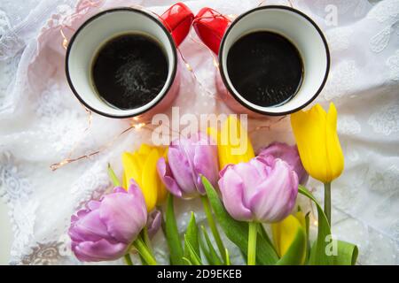 Schöner Morgen, zwei Tassen Kaffee und ein Bouquet von hellen Tulpen. Stockfoto