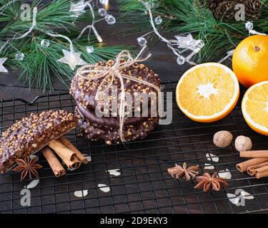 Advent- und Weihnachtsstimmung, Elisenlebkuchen mit Schokoladenvereisung und Haselnusskernen, wunderschön dekoriert auf einem dunklen Holztisch im Hintergrund Stockfoto