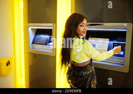 afroamerikanische Frau, die Geld von einem Geldautomaten abzieht, ATM-Konzept. Stockfoto