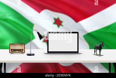 Burundi Nationalflagge Hintergrund mit Arbeitsplatz, Desktop-Computer und Office-Zubehör auf weißem modernen Tisch. Stockfoto