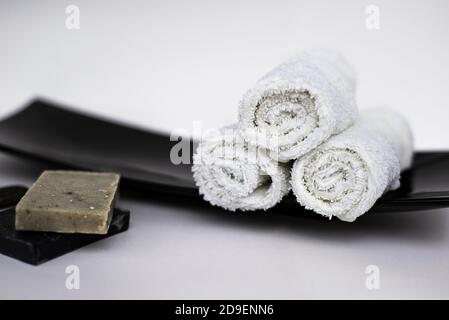 SPA und Gesichts- und Körperpflege-Konzept. Rollen von weißen Handtüchern und handgemachte Seifenstücke. Zen-Stil. Platz für Text kopieren. Stockfoto