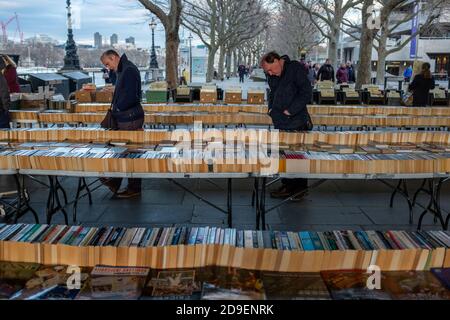 Zwei Männer, die unter einer Brücke auf einem längst etablierten Markt für gebrauchte Bücher am Ufer der Themse in London die Reihen der Bücher durchstöbern, die zum Verkauf angeboten werden. 05. März 2015. Foto: Neil Turner Stockfoto