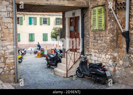 SIBENIK, KROATIEN - 2. OKTOBER 2018: Die Straße von Sibenik, Kroatien, mit Bogen, Veranda, Motorräder und Fenster mit grünen Fensterläden Stockfoto