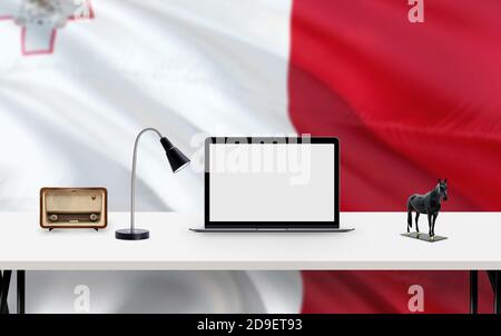 Malta Nationalflagge Hintergrund mit Arbeitsplatz, Desktop-Computer und Office-Zubehör auf weißem modernen Tisch. Stockfoto