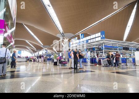 Reisende, die durch die Gegend gehen und ihre Abfertigungsschalter am identifizieren Hauptabflugshalle des Flughafens KLIA Stockfoto