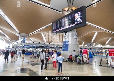 Reisende, die durch die Gegend gehen und ihre Abfertigungsschalter am identifizieren Hauptabflugshalle des Flughafens KLIA Stockfoto