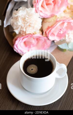 Morgen Tasse Kaffee und ein schönes Bouquet Rosen Blumen Auf dem Tisch Stockfoto