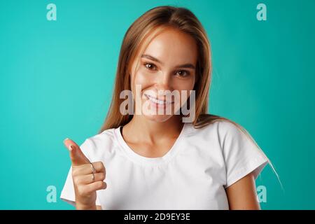 Positive junge blonde Frau, die auf die Kamera schaut und darauf zeigt Sie Stockfoto