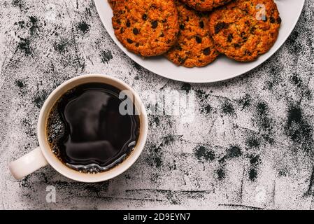 Kaffeetasse und Schokoladenkekse auf einem weißen Teller. Köstliche hausgemachte Kuchen. Frühstück am Morgen, Kaffeepause. Süßes Essen. Draufsicht, flach liegend Stockfoto