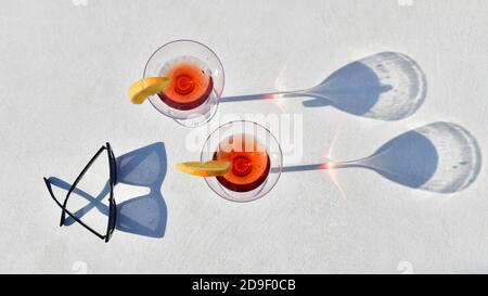 Top-down-Aufnahme von zwei Cocktails in der Nähe einer Brille auf einem unscharf-hellen Hintergrund. Lifestyle- und Freizeitkonzept. Stockfoto