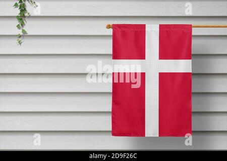 Dänemark nationale kleine Flagge hängt von einem Pfostenzaun entlang der Holzmauer in einer ländlichen Stadt. Konzept des Unabhängigkeitstages. Stockfoto