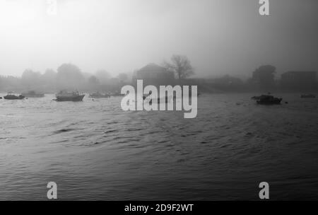 Boote auf einem Fluss im Nebel in schwarz und weiß Stockfoto