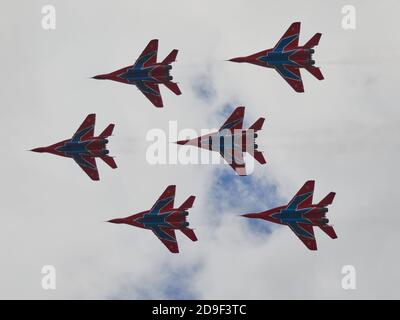 Sechs MiG-29-Kämpfer fliegen in dichter Formation direkt über dem Publikum am Himmel über dem Flugplatz.Flugschau auf dem Flugplatz Kubinka während des internationalen Forums der Armee-2020 des russischen Verteidigungsministeriums. Die Flugschau in Kubinka ist einer der Höhepunkte des Militärforums der Armee 2020. Es findet in der Regel parallel zu den Armeespielen. Im Jahr 2020 führten sie Kunstflug am Himmel durch: Mi-28 Kampfhubschrauber, das Swifts Kunstflugteam auf der MiG-29, die russischen Ritter auf der Su-30SM und Su-35S sowie die einzige Gruppe in Russland auf Sportkolbenflugzeugen „der erste Flug“. Ein Stockfoto