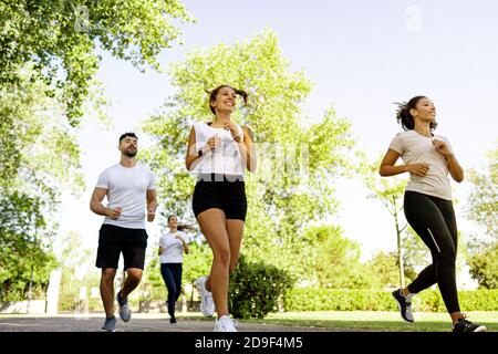 Gruppe von jungen multirassischen glücklichen Menschen tun Joggen in der Morgen im Park - multiethnische Freunde trainieren tagsüber Gemeinsam in der Natur laufen - H Stockfoto