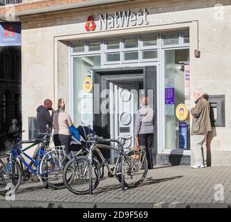 Kunden bilden während der Coronavirus-Krise im November 2020 eine geordnete Warteschlange außerhalb der NatWest Bank, Cambridge, England. Stockfoto