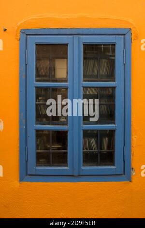 Ein hellblauer Fensterrahmen in einer leuchtend orangefarbenen Wand in der Stadt Oia auf der griechischen Ferieninsel Santorini. 20. Oktober 2015. Foto: Neil Turner Stockfoto