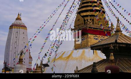 Nahaufnahme von religiösen Tempeln und einer Stupa mit bunten Gebetsfahnen im buddhistischen Tempelkomplex Swayambhunath auf einem Hügel. Stockfoto