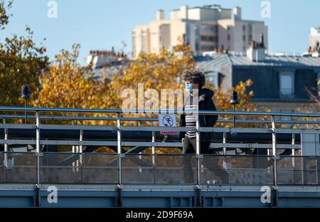 Kaukasischer Mann mit Schutzmaske und Spaziergang in der französischen Hauptstadt während der nationalen Sperre Frankreichs. Herbstlandschaft im Hintergrund. Stockfoto