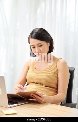Junge schwangere Mitarbeiter im Büro Stockfoto