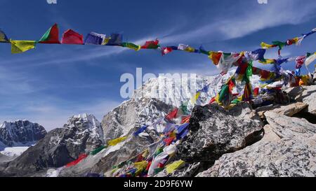 Aussichtspunkt auf dem Gipfel des Berges Kala Patthar mit farbenfrohen buddhistischen Gebetsfahnen, die im starken Wind fliegen, und schneebedeckten Himalaya-Bergen. Stockfoto