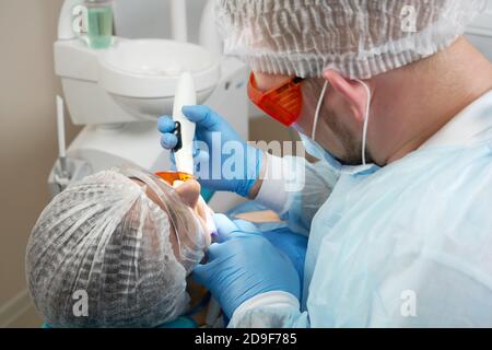 Zahnarzt tun Verfahren mit zahnmedizinischen Härtung mit UV-Licht in der Klinik Stockfoto