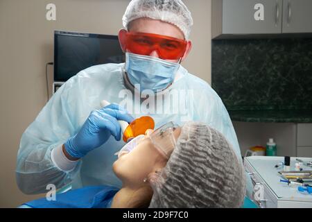 Zahnarzt tun Verfahren mit zahnmedizinischen Härtung mit UV-Licht in der Klinik Stockfoto