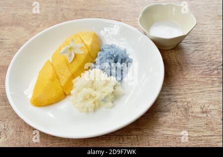 Reifen Sie Mango mit weißen und lila klebrigen Reis Dressing Kokosnuss Milch auf dem Teller Stockfoto