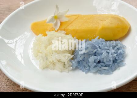 Reifen Sie Mango mit weißen und lila klebrigen Reis Dressing Kokosnuss Milch auf dem Teller Stockfoto