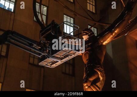 NEW YORK, NY - 04. NOVEMBER 2020: Ein Arbeiter legt eine Gesichtsmaske für die Atlas-Skulptur vor dem Rockefeller Plaza 45 an. Stockfoto