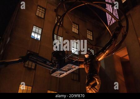 NEW YORK, NY - 04. NOVEMBER 2020: Ein Arbeiter legt eine Gesichtsmaske für die Atlas-Skulptur vor dem Rockefeller Plaza 45 an. Stockfoto