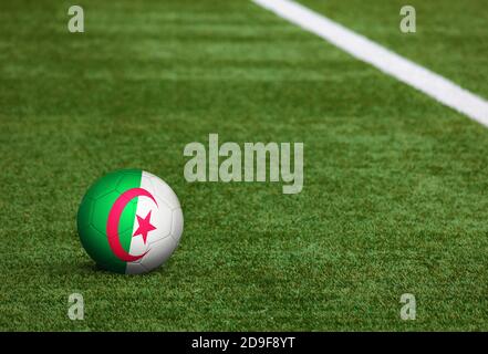 Algerien Flagge auf Ball auf Fußballplatz Hintergrund. Fußball-Nationalthema auf grünem Gras. Konzept des Sportwettbewerbs. Stockfoto