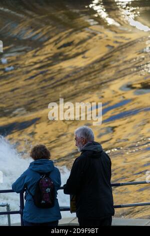 Ein älterer Mann und eine ältere Frau standen neben dem Fluss Aire Weir nutzt die Aussicht, Shipley, West Yorkshire, England, Großbritannien. Stockfoto
