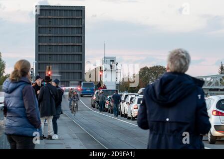 Zingst, Deutschland. Oktober 2020. Dutzende Touristen stehen auf der Meinigbrücke, um Kraniche zu beobachten. (l) auf der anderen Straßenseite (r) warten Autofahrer darauf, dass die erhöhte Liftbrücke wieder für den Verkehr geöffnet wird. Die Meininger Brücke verbindet das Festland mit der Halbinsel Fischland-Darß-Zingst. Die Brücke war Teil einer Eisenbahnlinie von 1910. In der Zwischenzeit ist ein Neubau für die Eisenbahn, Autos, Radfahrer und Fußgänger geplant. Quelle: Stephan Schulz/dpa-Zentralbild/ZB/dpa/Alamy Live News Stockfoto