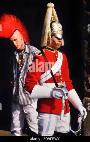 Punk Rocker Matt Belgrano, 'The Postcard Punk' steht mit einem Mitglied der Household Cavalry, Horse Guards Parade, London, England, UK, um 1980 Stockfoto