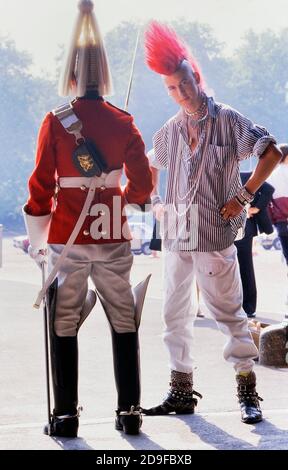 Punk Rocker Matt Belgrano, 'The Postcard Punk' steht mit einem Mitglied der Household Cavalry, Horse Guards Parade, London, England, UK, um 1980 Stockfoto