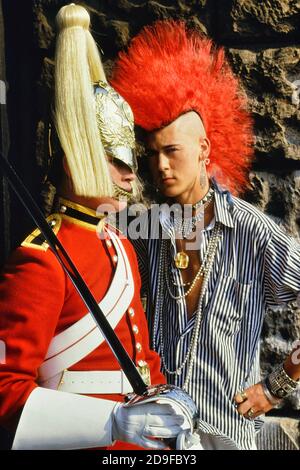 Punk Rocker Matt Belgrano, 'The Postcard Punk' steht mit einem Mitglied der Household Cavalry, Horse Guards Parade, London, England, UK, um 1980 Stockfoto