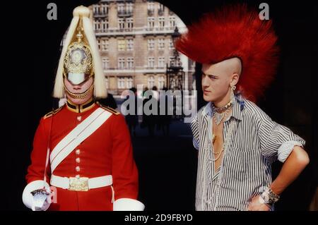 Punk Rocker Matt Belgrano, 'The Postcard Punk' steht mit einem Mitglied der Household Cavalry, Horse Guards Parade, London, England, UK, um 1980 Stockfoto