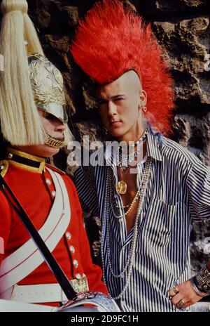 Punk Rocker Matt Belgrano, 'The Postcard Punk' steht mit einem Mitglied der Household Cavalry, Horse Guards Parade, London, England, UK, um 1980 Stockfoto