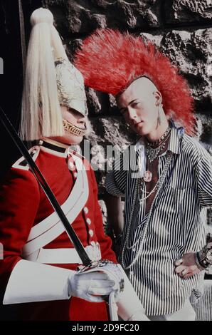 Punk Rocker Matt Belgrano, 'The Postcard Punk' steht mit einem Mitglied der Household Cavalry, Horse Guards Parade, London, England, UK, um 1980 Stockfoto