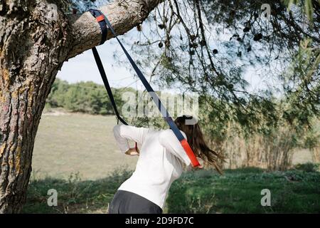 TRX Sport Team. Junge Frau macht Übungen im Freien in einem Park. Riemen Stockfoto