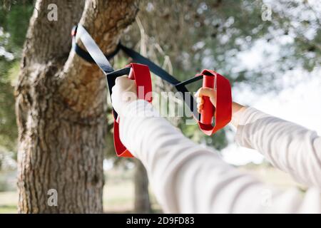 TRX Sport Team. Junge Frau macht Übungen im Freien in einem Park. Riemen Stockfoto