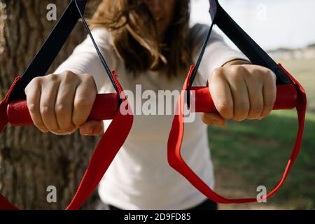 TRX Sport Team. Junge Frau macht Übungen im Freien in einem Park. Riemen Stockfoto