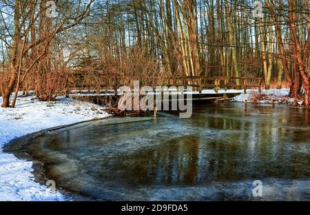 Holzbrücke über den gefrorenen Malenter Au (kleiner Fluss in Holstein Schweiz). Stockfoto