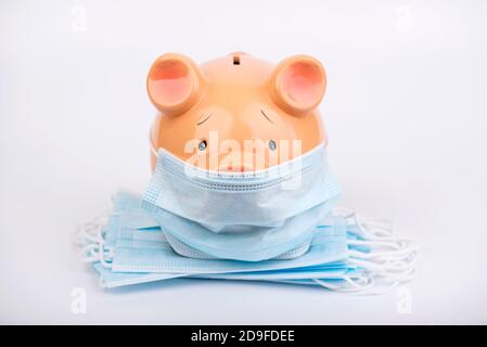Covid 19 Konzept. Sparschwein mit Haufen von medizinischen Gesichtsmasken isoliert background.Health Konzept Stockfoto
