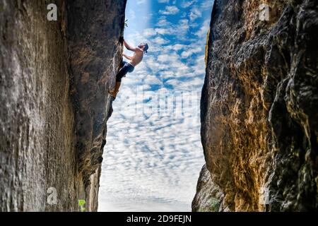 Junger Mann frei solo Klettern eine vertikale Wand ohne Seil Und zwischen zwei Wänden Stockfoto