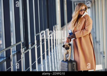 Junge Beifahrerin in warmen Kleidern, die mit ihrem Hund unterwegs ist In der Flughafenhalle Stockfoto