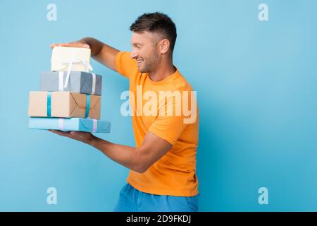 Mann in T-Shirt Blick auf eingewickelte Geschenke auf blau Stockfoto