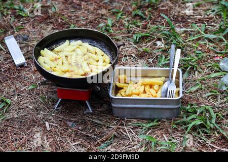 Der Prozess der Bratkartoffeln im Freien mit einem roten Mini Gasherd und schwarze Bratpfanne Stockfoto