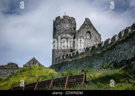 Bezdez, Tschechische Republik - Juli 19 2020: Ein Turm und ein Haus, Teile der mittelalterlichen Burg aus grauen Steinen auf einem Hügel. Sonniger Tag, Wolken. Stockfoto